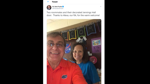A screenshot featuring a tweet of President Fuchs posing with a resident adviser at Jennings Hall before a door decorated by two roommates.  